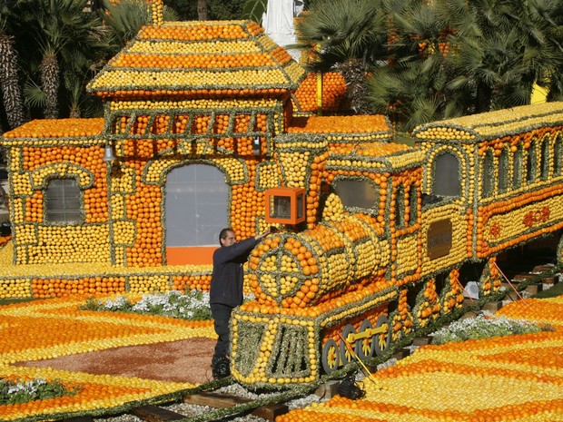 Trabalhador faz últimos ajustes em trem feito com limões e laranjas, durante o 80° Festival do Limão em Menton, no sul da França. Neste ano, o tema do festival, que envolve mais de 145 toneladas de frutas cítricas, é 'Volta ao Mundo em 80 dias' (Foto: Lionel Cironneau/AP)