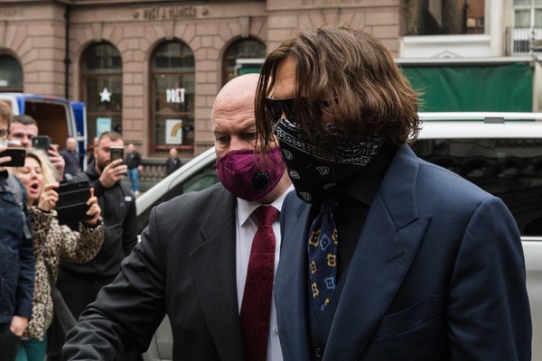 O ator Johnny Depp chegando com uma máscara no rosto ao julgamento do processo movido por ele contra o jornal inglês The Sun (Foto: Getty Images)