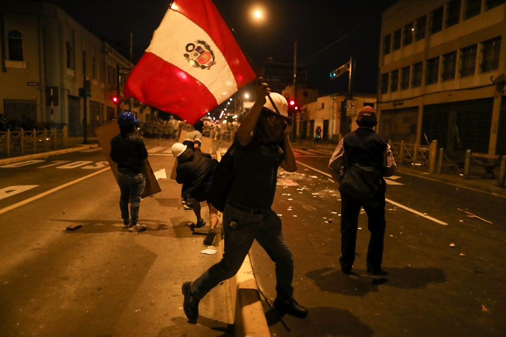 Manifestante com a bandeira do Peru em marcha que pede a renúncia da presidente Dina Boluarte; houve confronto com a polícia — Foto: Sebastian Castaneda/Reuters