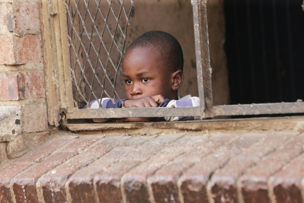 Uma criança olha para a rua da janela de sua prédio em Harare, no Zimbábue, em 30 de março. O país está em isolamento por 21 dias em um esforço para conter a propagação do coronavírus — Foto:  Tsvangirayi Mukwazhi/AP