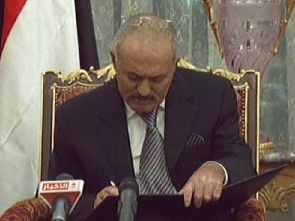 Imagem de arquivo da TV estatal saudita mostra o momento em que Ali Abdullah Saleh assina acordo para deixar o poder no Iêmen  (Foto: AFP)