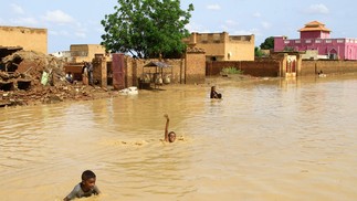 Crianças sudanesas nadam nas águas da enchente na cidade de Iboud, 250 km ao sul da capital Cartum  — Foto: EBRAHIM HAMID / AFP