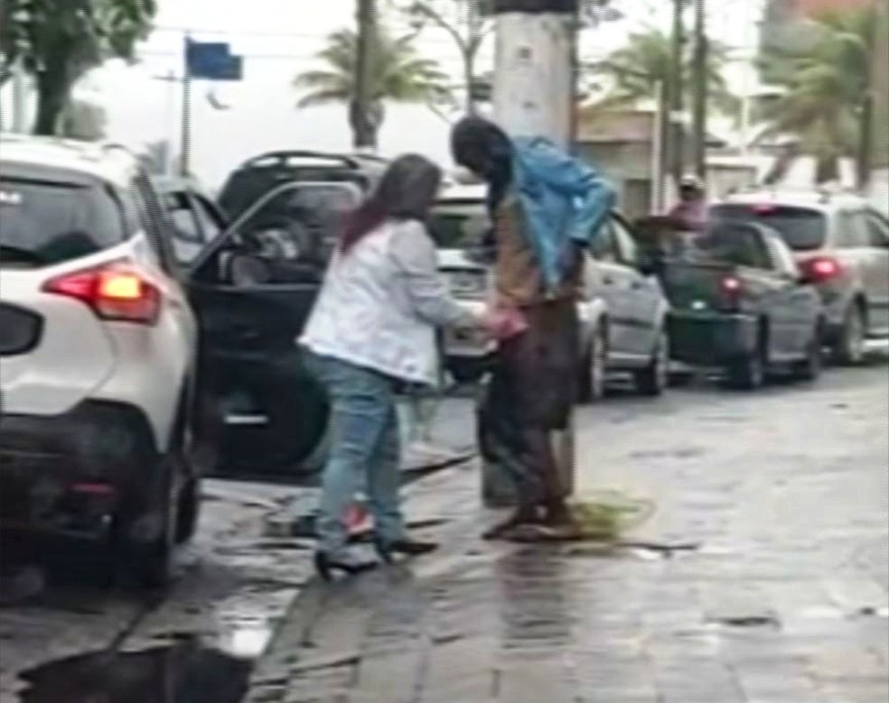 Mulher desceu de veículo e agasalhou morador de rua em São Vicente, SP — Foto: Reprodução