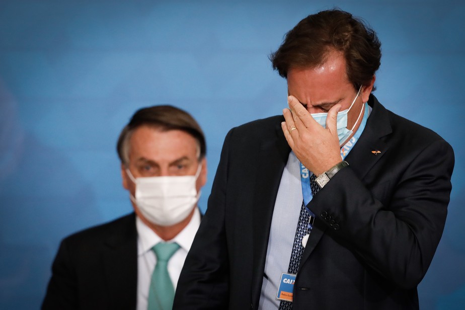 O presidente Jair Bolsonaro observa observa Pedro Guimarães, que preside a Caixa, em cerimônia no Planalto