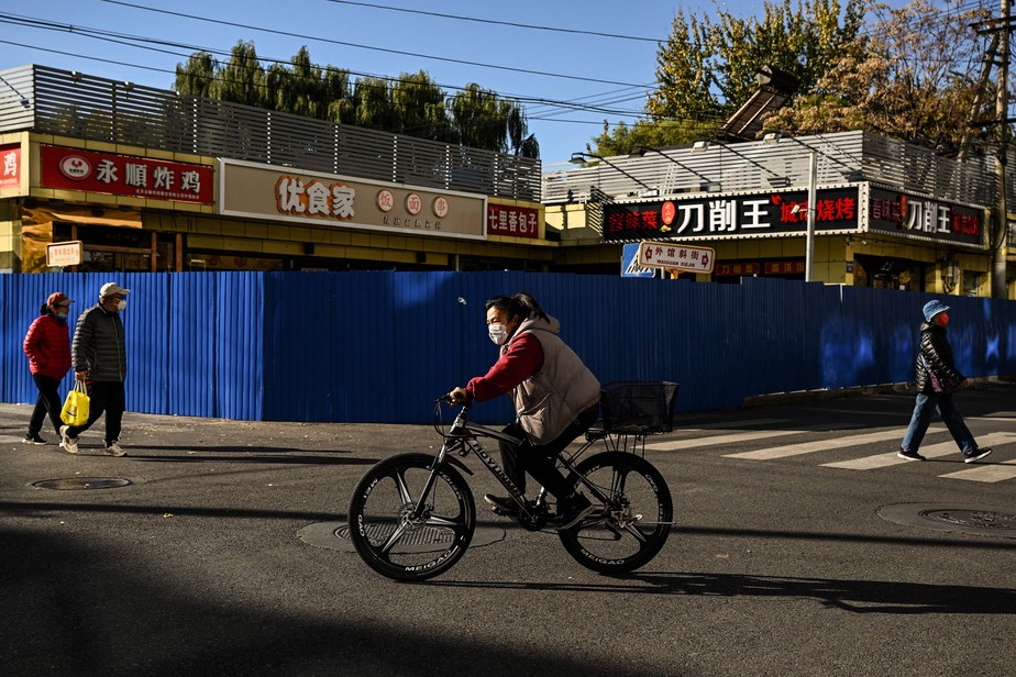 Ciclista em área fechada por quarentena em Pequim, sob o céu azul: nuvem de poluição ficou para trás