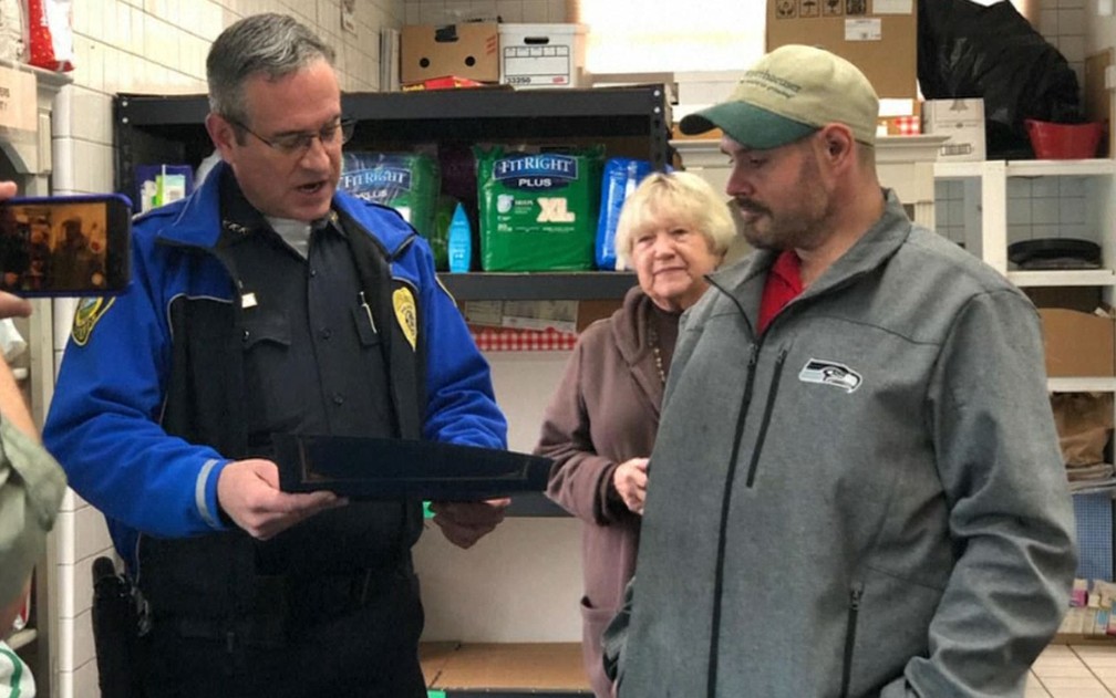 O chefe de polÃ­cia Brad Moericke entrega homenagem a Kevin Booth no Sumner Food Bank, em Washington â Foto: NBC