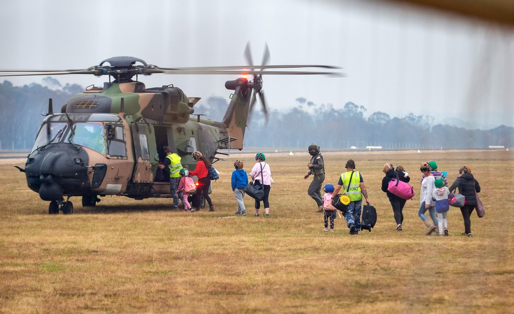 5 de janeiro - Foto divulgada pelo Departamento de Defesa da Austrália mostra pessoas embarcando em um helicóptero quando a comunidade de Mallacoota devastada pelo fogo é evacuada — Foto: Nicole Dorrett/ADF via AP