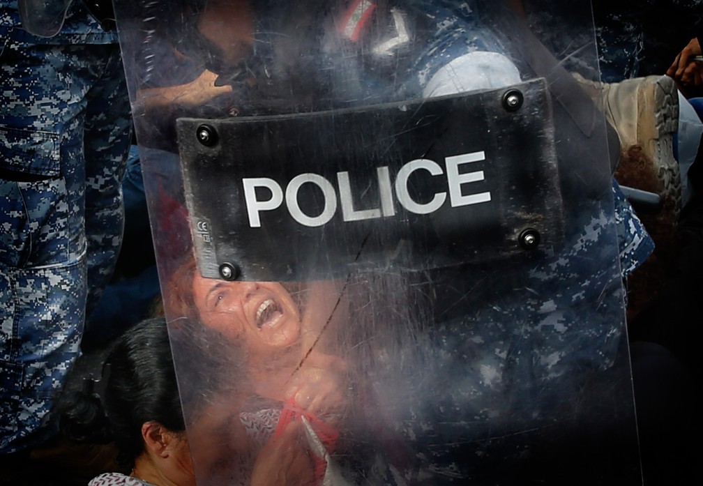 26 de outubro - Um policial da tropa de choque retira manifestantes contra o governo que bloqueavam uma rodovia em Beirute, no Líbano. Os protestos de escala nacional no país tinham como alvo a classe política, acusada de abusar do poder e de explorar os recursos do Estado em benefício próprio — Foto: Hussein Malla/AP