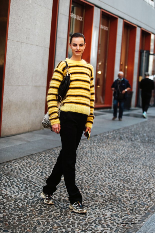 MILAN, ITALY - SEPTEMBER 22: Estella Brons wears a fuzzy yellow and brown sweater, Dior saddle bag, black jeans, net bag, and Salomon sneakers after the Giada show during Milan Fashion Week Spring/Summer 2022 September 22, 2021 in New York City. (Photo by (Foto: Getty Images)