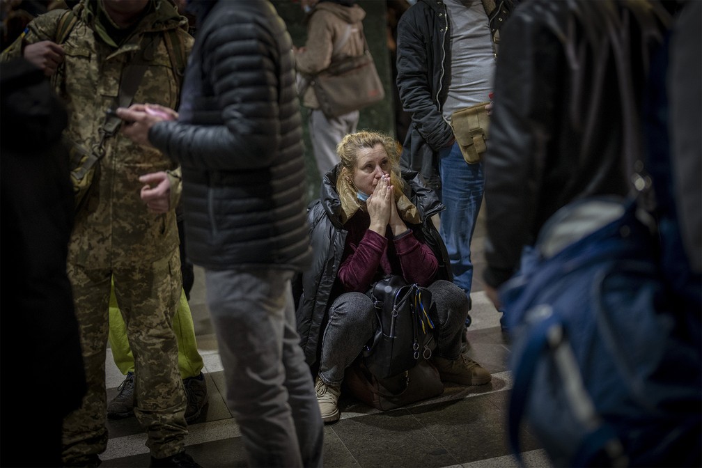 Uma mulher reage enquanto espera por um trem tentando deixar Kiev, Ucrânia, nesta quinta-feira (24) — Foto: Emilio Morenatti/AP