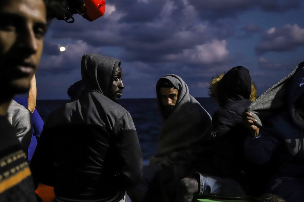 19 de outubro - Migrantes são vistos no convés do navio de resgate Sea Watch-3 na zona de busca e resgate maltesa do Mar Mediterrâneo. Nos dois dias anteriores, o navio resgatou 412 migrantes de sete barcos diferentes em perigo e estava pedindo um porto seguro para desembarcar — Foto: Valeria Mongelli/AP