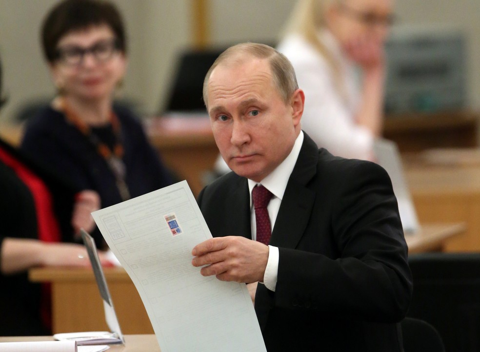 Putin com a cédula de votação na mão em Moscou neste domingo (18) (Foto: Sergei Chirkov/POOL via Reuters)