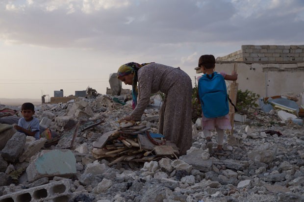 Mulher e crianças em meios aos destroços na cidade síria de Kobane; cidade foi destruída em combates com Estado Islâmico (Foto: Gabriel Chaim/G1)