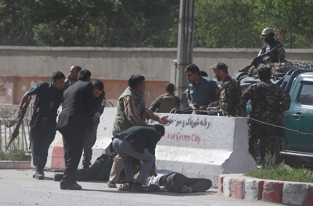 Policiais ajudam jornalistas afegãos que foram atingidos por explosão em Cabul, nesta segunda-feira (30) (Foto: Omar Sobhani/Reuters)