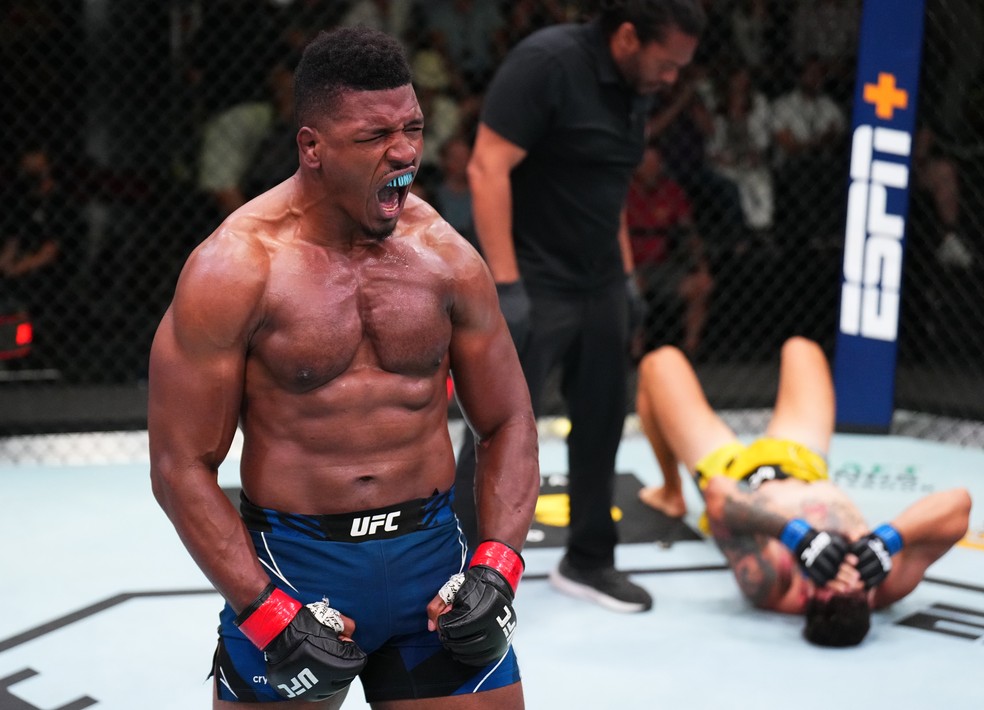 Alonzo Menifield (esq.) vibra muito após vencer Askar Mozharov (dir, fundo) — Foto: Chris Unger/Zuffa LLC