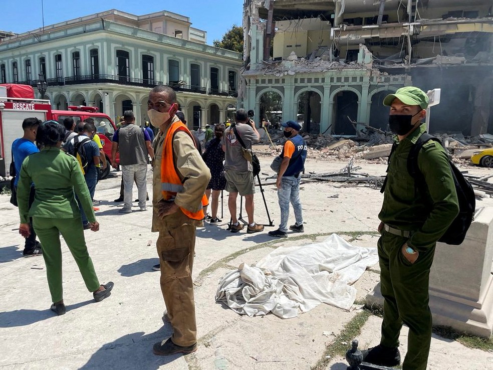 Unidades de emergência cubanas aparecem junto de corpo coberto em frente ao Hotel Saratoga — Foto: Alexandre Meneghini/REUTERS