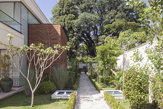 Casa é rodeada por jardim com flores, horta e caminhos delicados (Foto: Divulgação)