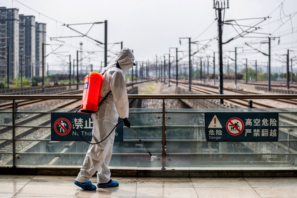 Funcionário desinfecta estação de trem em Wuhan, marco zero da pandemia — Foto: AFP