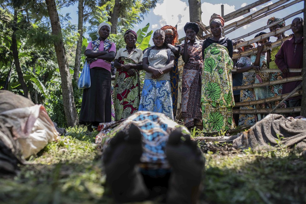 Mulheres de vilarejo no leste da República Democrática do Congo observam corpos enfileirados após chuvas torrenciais que deixaram mais de 400 mortos na região, em 6 de maio de 2023.   — Foto: Moses Sawasaw/ AP 