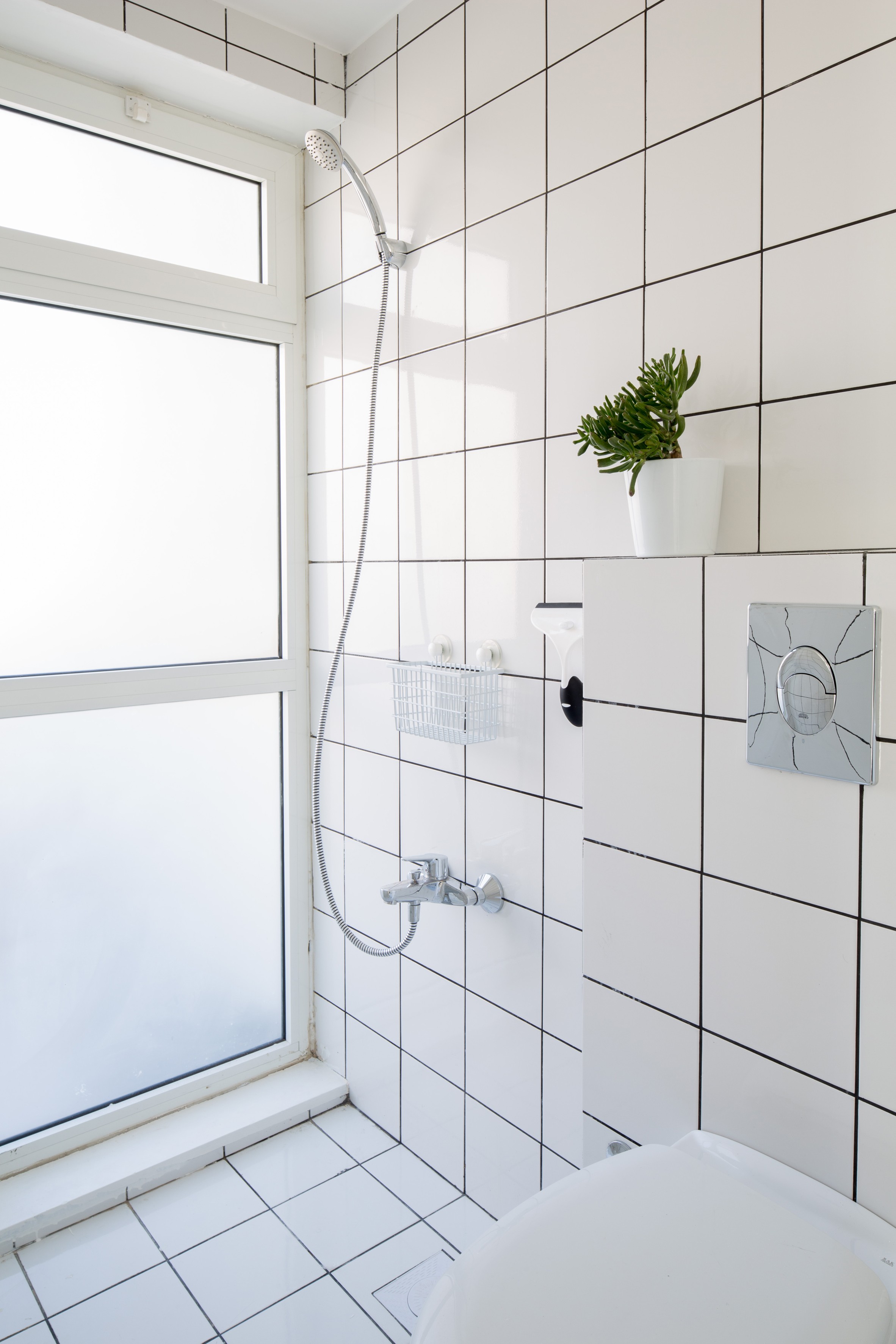 As áreas de cozinha e do banheiro são revestidas em azulejos brancos combinando com o rejunte preto  (Foto: Reprodução/Dezeen)