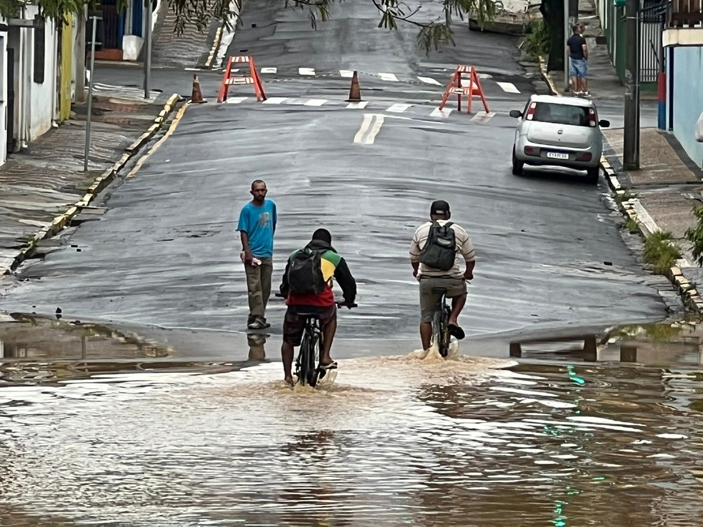 Ciclistas atravessam via alagada em Capivari nesta quinta-feira (29) — Foto: Giuliano Tamura/ EPTV