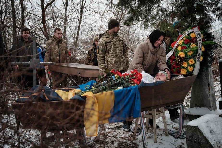 Mulher vela o caixão de soldado ucraniano morto em Bakhmut, em um cemitério em Sloviansk