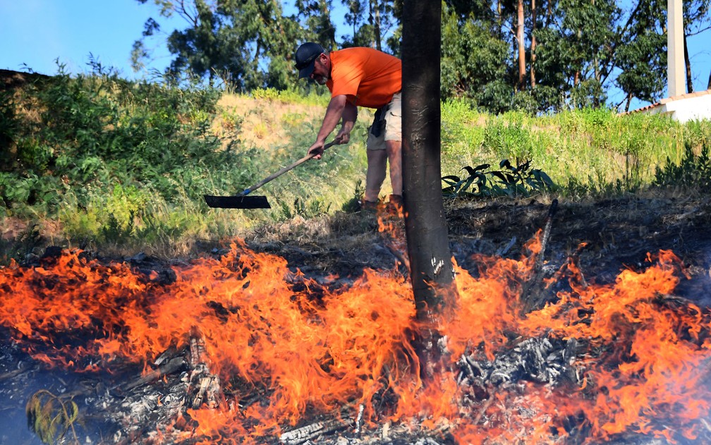 Um homem tenta extinguir chamas de incêndio florestal em Bormes-les-Mimosas, na França, na quarta-feira (26) (Foto: Anne-Christine Poujoulat/AFP)