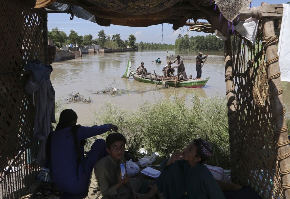 Pessoas desabrigadas transportam pertences após cheias históricas de agosto no Paquistão, nos arredores de Peshawar. — Foto: AP Photo/Mohammad Sajjad