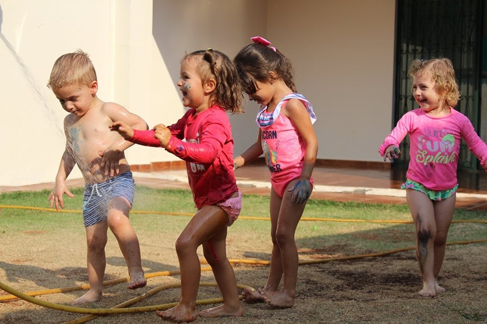 Criança durante banho de mangueira em escola de Campo Grande — Foto: Taise Cardoso/Divulgação