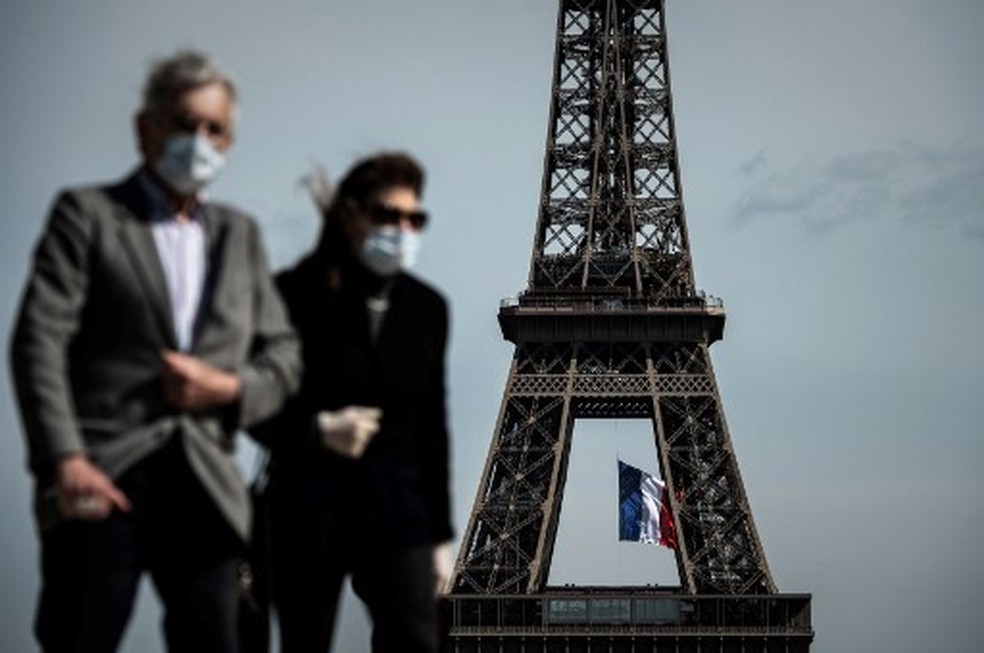 Casal com máscaras caminha em frente à Torre Eiffel, em Paris, na França, em foto de maio — Foto: Philippe Lopez/AFP