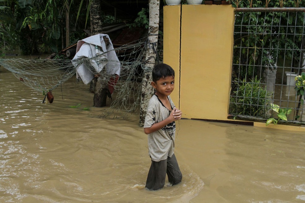Criança em enchente: pequenos serão mais expostos a temporais e inundações. — Foto: Getty Images