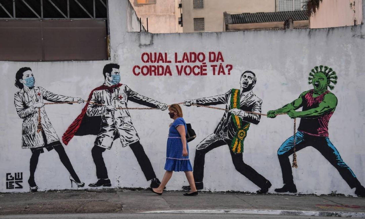 Um grafite representando o presidente Jair Bolsonaro e o novo coronavírus contra profissionais de saúde, em São Paulo — Foto: NELSON ALMEIDA / AFP
