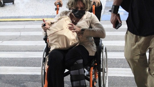 Com o pé fraturado, Susana Vieira desembarca no Rio com auxílio de cadeira de rodas