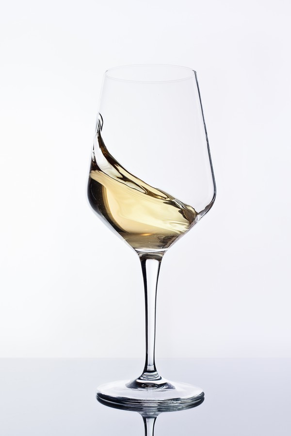 Close up of white wine swirling into glass on a white background. Studio shot. (Foto: Getty Images)