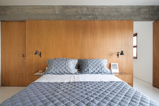 Quarto. A parede revestida de carvalho-americano traz calor ao espaço. Sobre a cama, roupa da Trousseau; nas laterais, luminárias da Reka (Foto: Maíra Acayaba / Editora Globo)