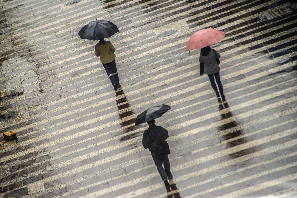 Pedestres se protegem do frio e da chuva no centro histórico da cidade de São Paulo. — Foto: CRIS FAGA/ESTADÃO CONTEÚDO