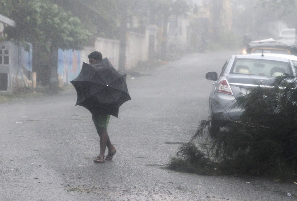Homem caminha nesta quinta-feira (11) em rua de Gopalpur, na Índia, durante chuvas levadas pelo ciclone Titli — Foto: AP Photo