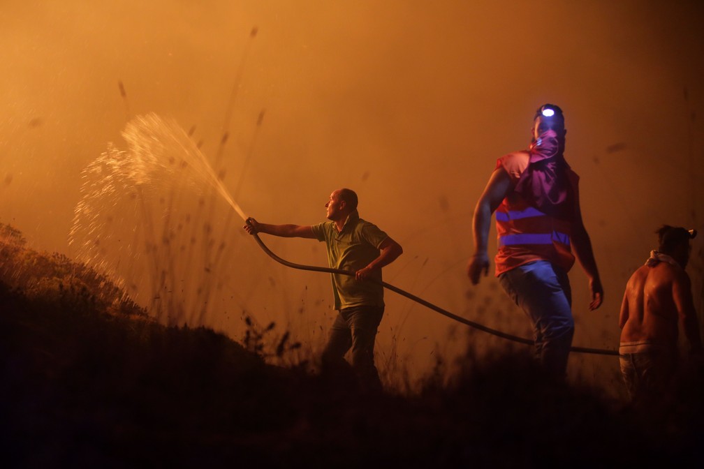 Voluntários combatem o incêndio que avançava sobre casas da região de Obidos, na madrugada desta segunda-feira (16)  (Foto: Armando Franca/ AP)