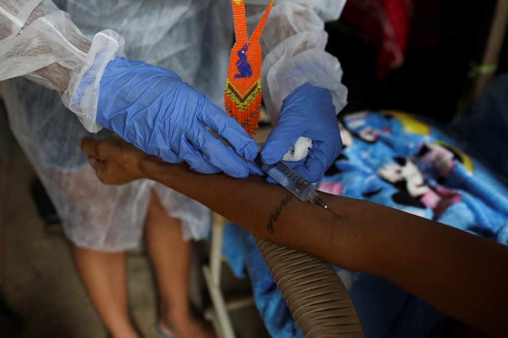 Vanda aplica uma injeção de dipirona em sua paciente Sabrina de Sales Benzaquem, de 34 anos, que estava com febre e suspeita de ter sido infectada pela COVID-19 — Foto: Bruno Kelly/Reuters