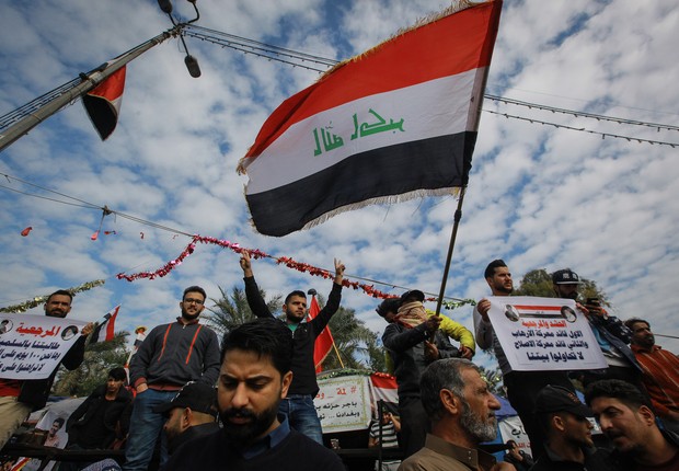 Iraque, Bagdá: Manifestantes antigovernamentais agitam uma bandeira nacional iraquiana durante uma manifestação na praça Tahrir, contra a violação da soberania iraquiana pelos EUA e Irã (Foto: Getty Images)