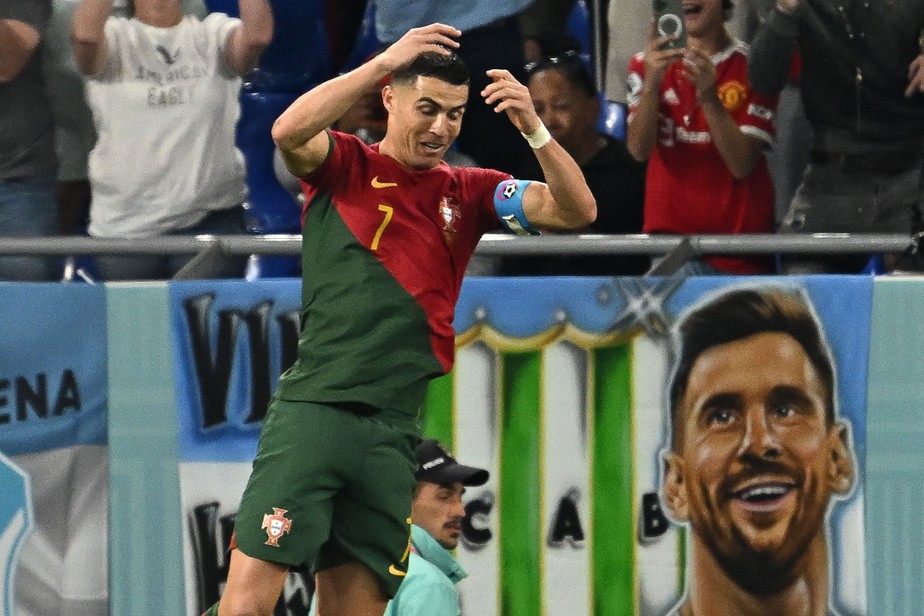 Cristiano Ronaldo celebra seu gol contra Gana com a pintura de Messi ao fundo