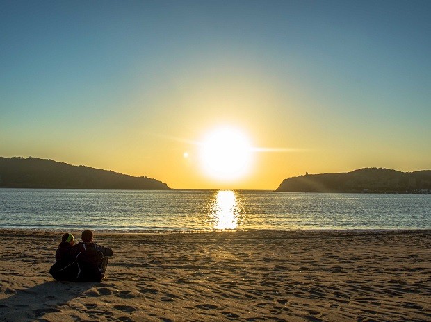 A publicitária Julie Assêncio e o administrador de redes Thiago Ruiz veem o pôr do sol em praia de Portugal (Foto: Diocá/Divulgação)
