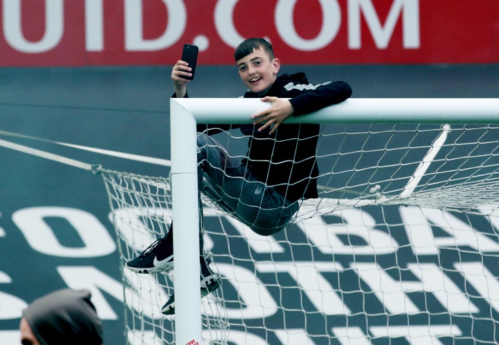 Torcedor se pendura na rede de um dols gols do Old Trafford — Foto: Reuters