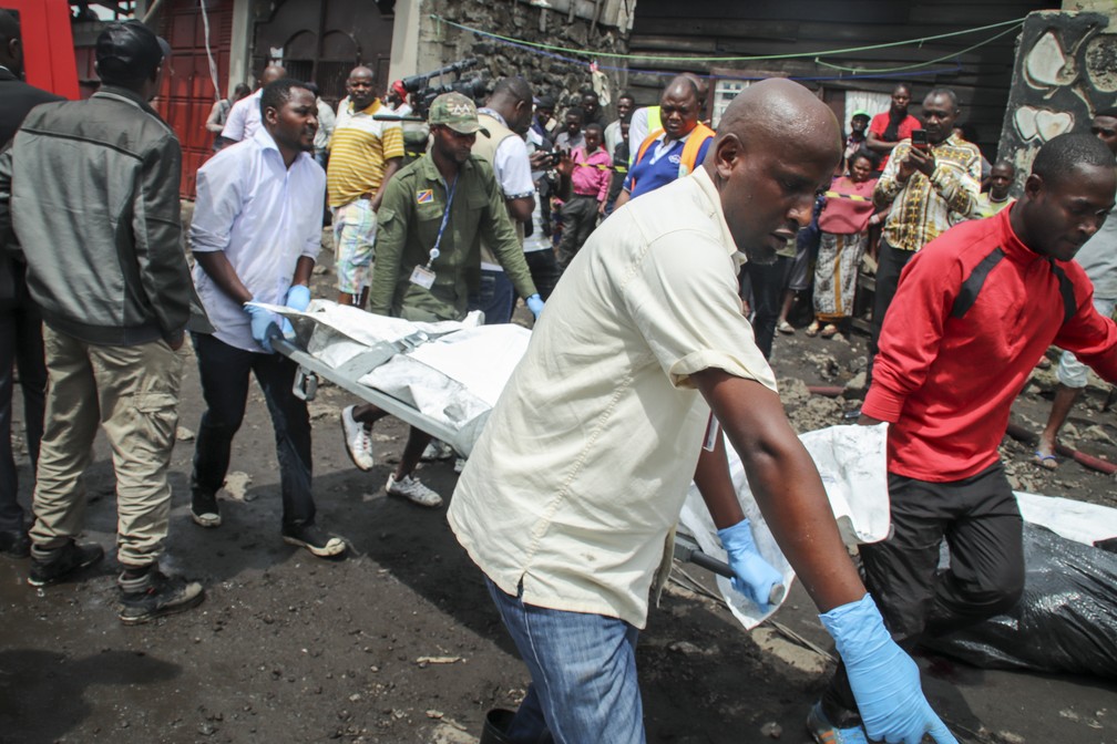 Equipes de resgate e observadores se reúnem em meio aos destroços de uma aeronave operada pela transportadora privada Busy Bee, que caiu em Goma, no Congo — Foto: Justin Kabumba/AP