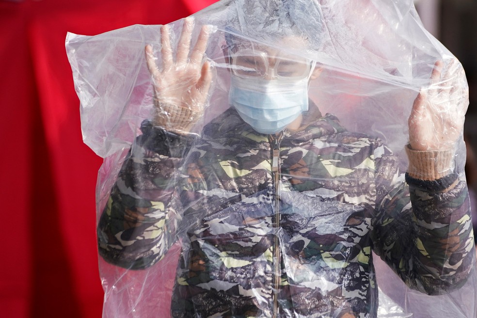 Homem veste saco plástico e máscara de proteção em Sangai, ele tenta se proteger em meio a epidemia de coronavírus na China — Foto: Aly Song / Reuters