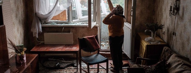 Lyubov Prokofjevna, 85 anos, fala ao telefone em seu apartamento danificado em um prédio atingido por um míssil, em Kharkiv, na Ucrânia — Foto: Yasuyoshi CHIBA / AFP