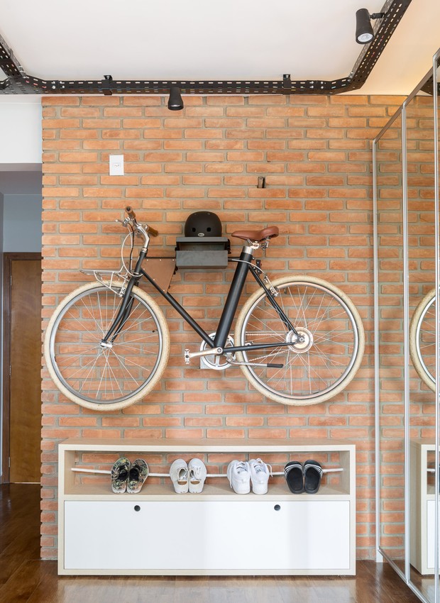 O suporte para bike e capacete também é obra da Caminho Oficina. Com a bicicleta elevada sobrou espaço para uma sapateira (Foto: Joana França/Divulgação)