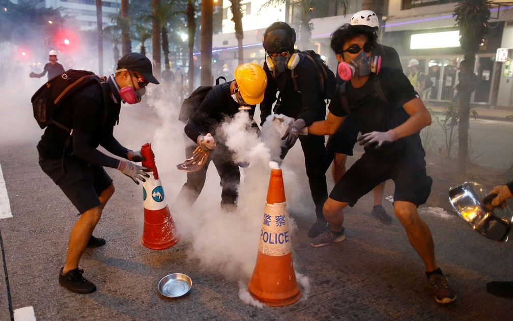 O mobiliário urbano de Hong Kong ganha novas funções nas mãos dos manifestantes: sinalizações de ruam servem para abafar efeito de bombas de gás lacrimogêneo — Foto: Reuters/Thomas Peter 