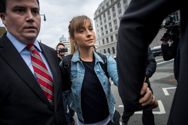 A atriz Allison Mack deixando a prisão na qual estava detida em Nova York na companhia de seus advogados (Foto: Getty Images)