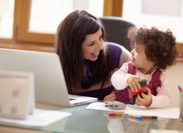 Mulher trabalhando com criança do lado (Foto: Shutterstock)